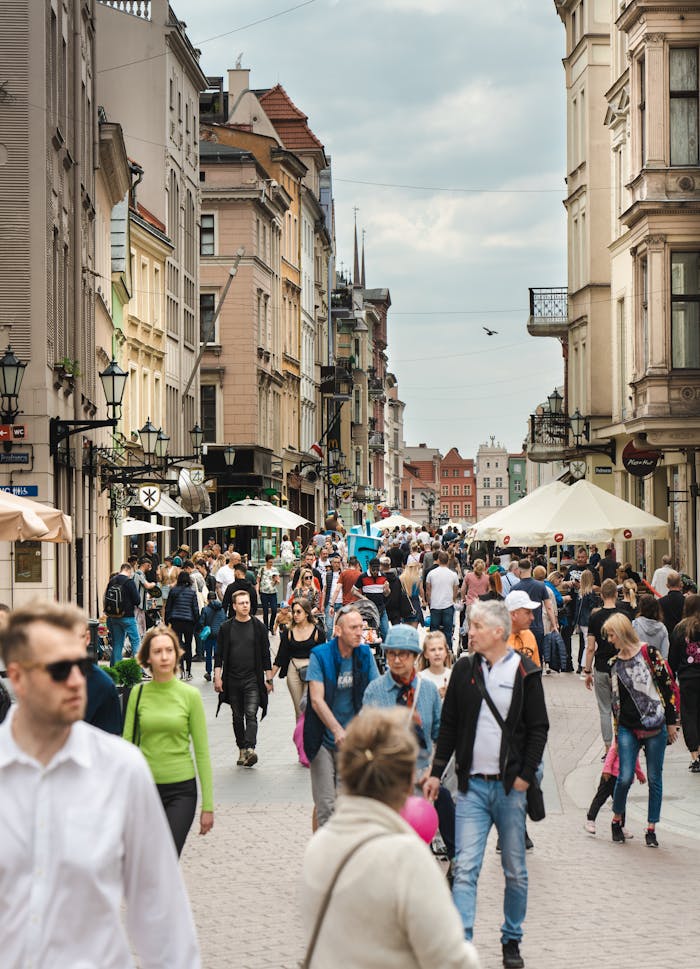 Vibrant street life in Toruń with people walking amidst historic buildings.
